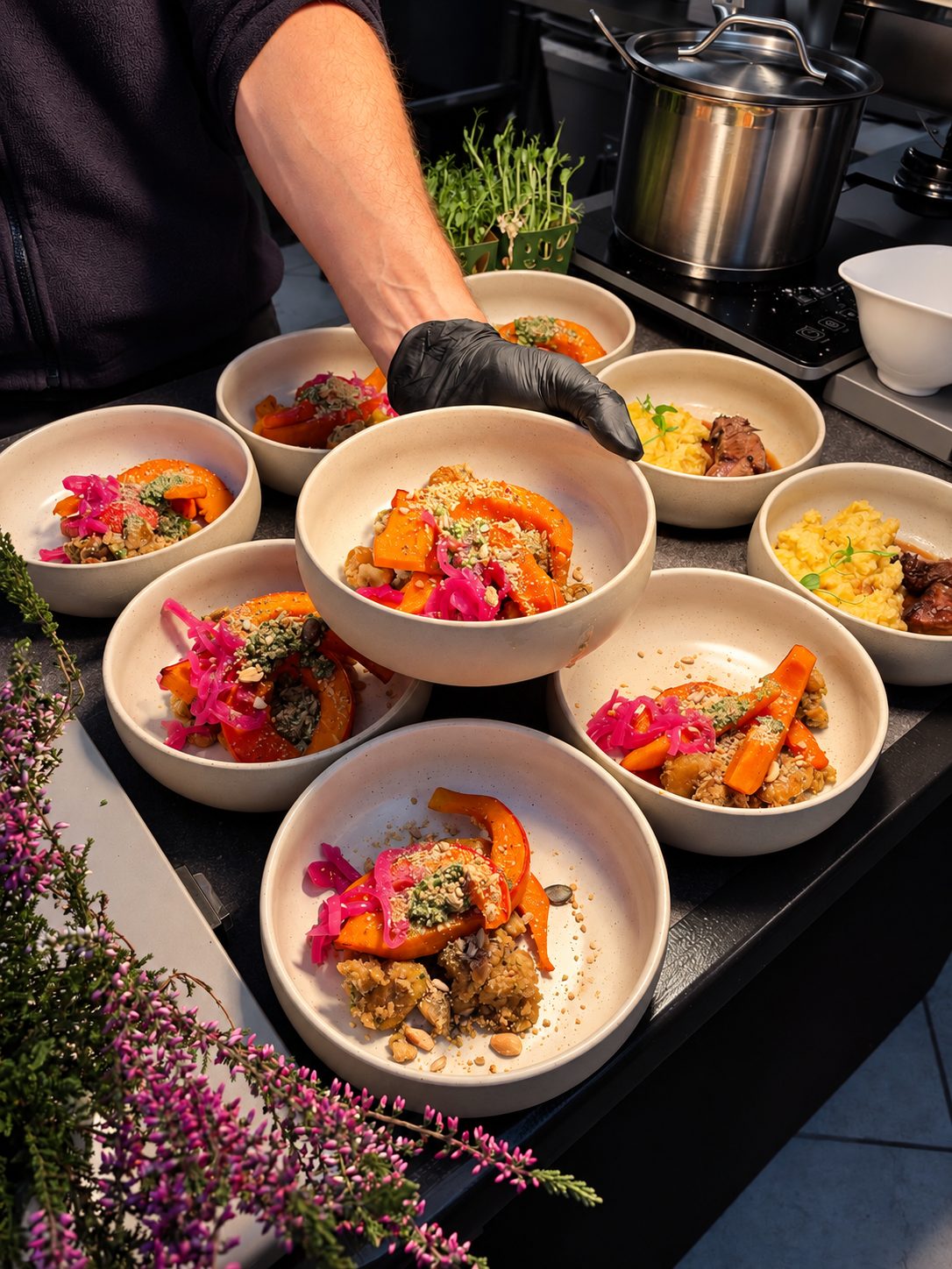 Chef plating autumn bowls with roasted squash, carrots and pickled red onion