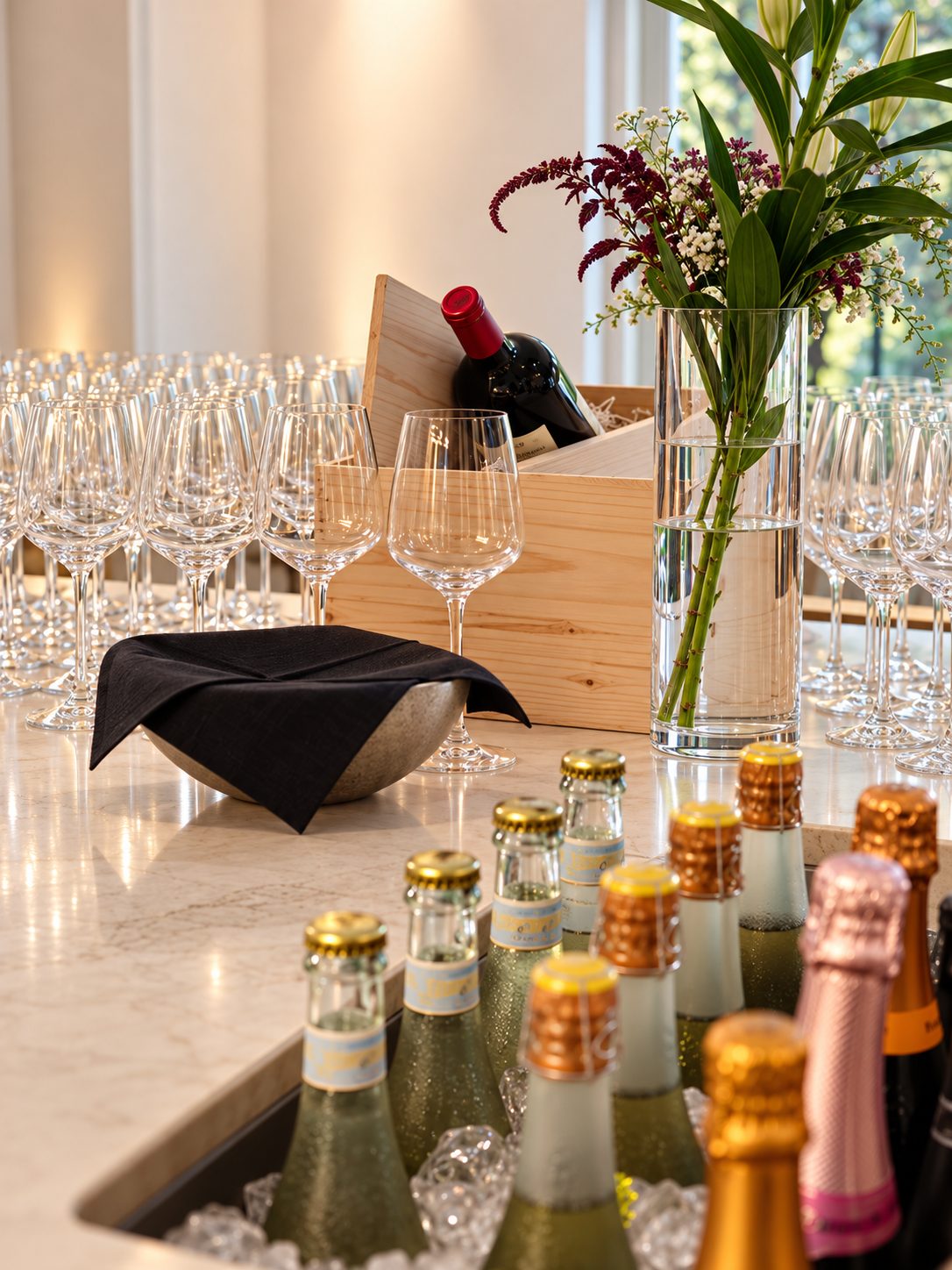 Bar with rows of wine glasses, chilled sparkling bottles and a flower vase